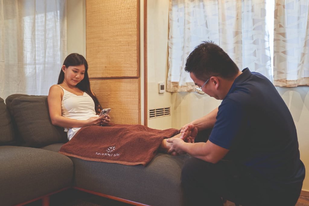 A picture showing a therapist performing a Foot Reflexology massage, where pressure is applied to specific points on the feet to promote relaxation and improve health.