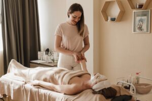 The client lies on a massage table, while the masseuse's skilled hands work on her hand.